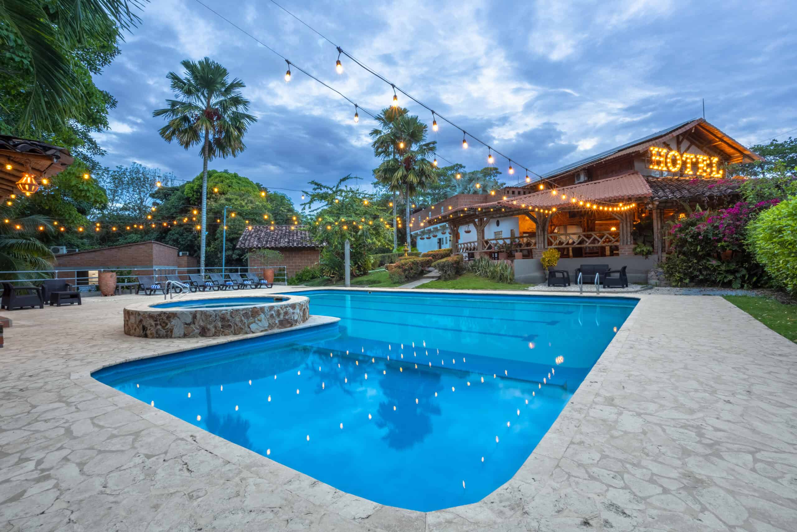 Piscina del Hotel Parador del Gitano al atardecer con iluminación cálida y palmeras